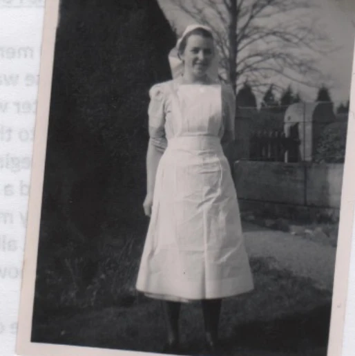 An old black and white photograph of June Hewett dressed in her NHS nurses uniform. She are standing outside in a garden. June is a member of the NHS Retirement Fellowship and has shared her story as part of the Member Stories series.